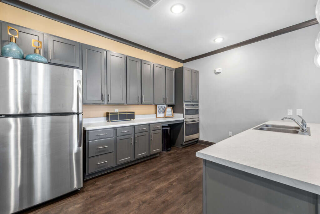 Community room kitchen equipped with stainless steel appliances, sleek cabinets, and hardwood flooring at Le Jolliet Apartments.