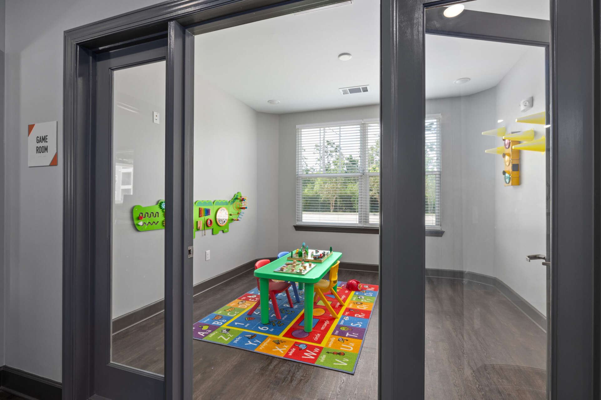 A children's play area featuring a small green table with toys and a large window at Le Jolliet Apartments.