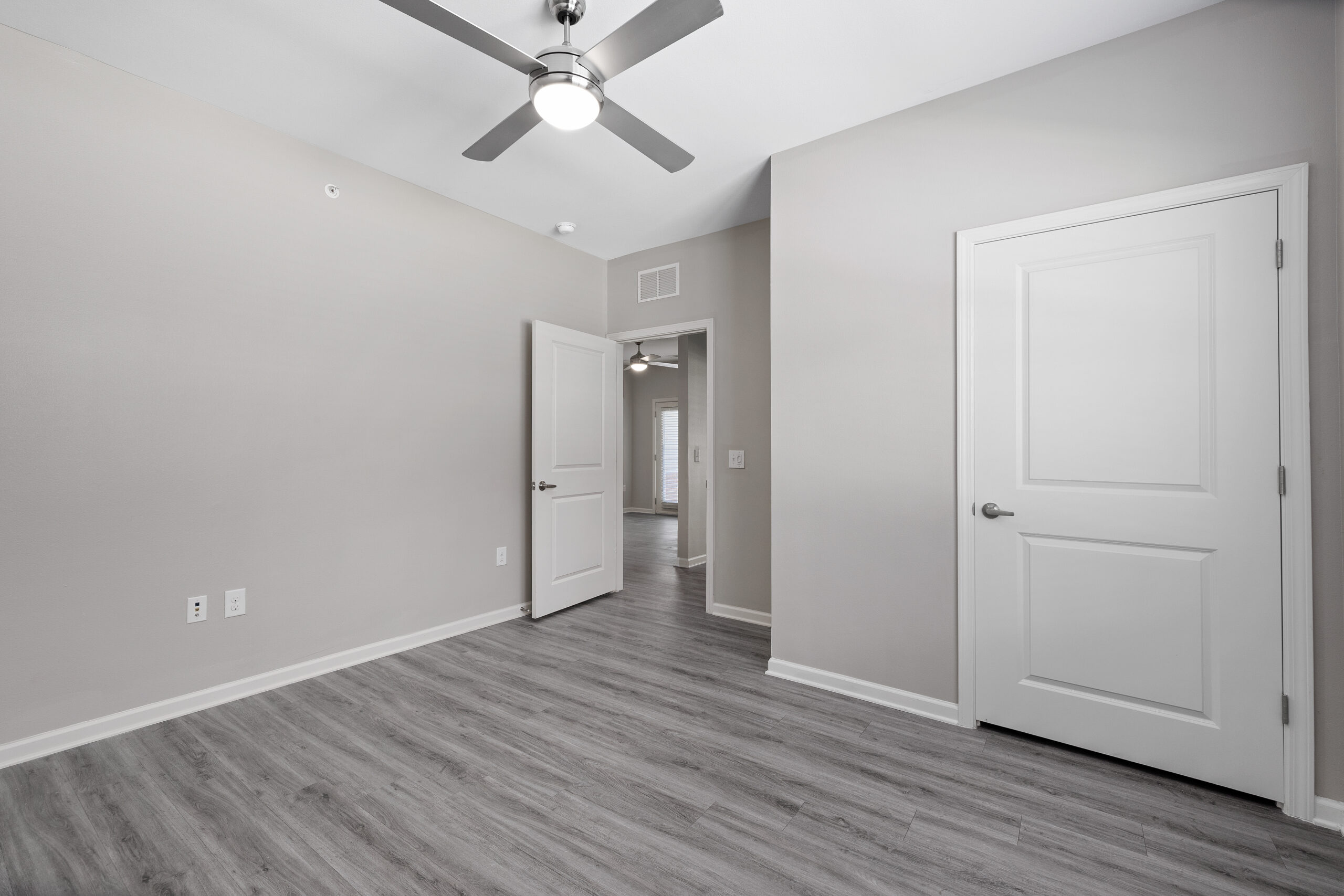 Spacious beige bedroom featuring hardwood-style floors at Le Jolliet Apartments in Lake Charles, LA.