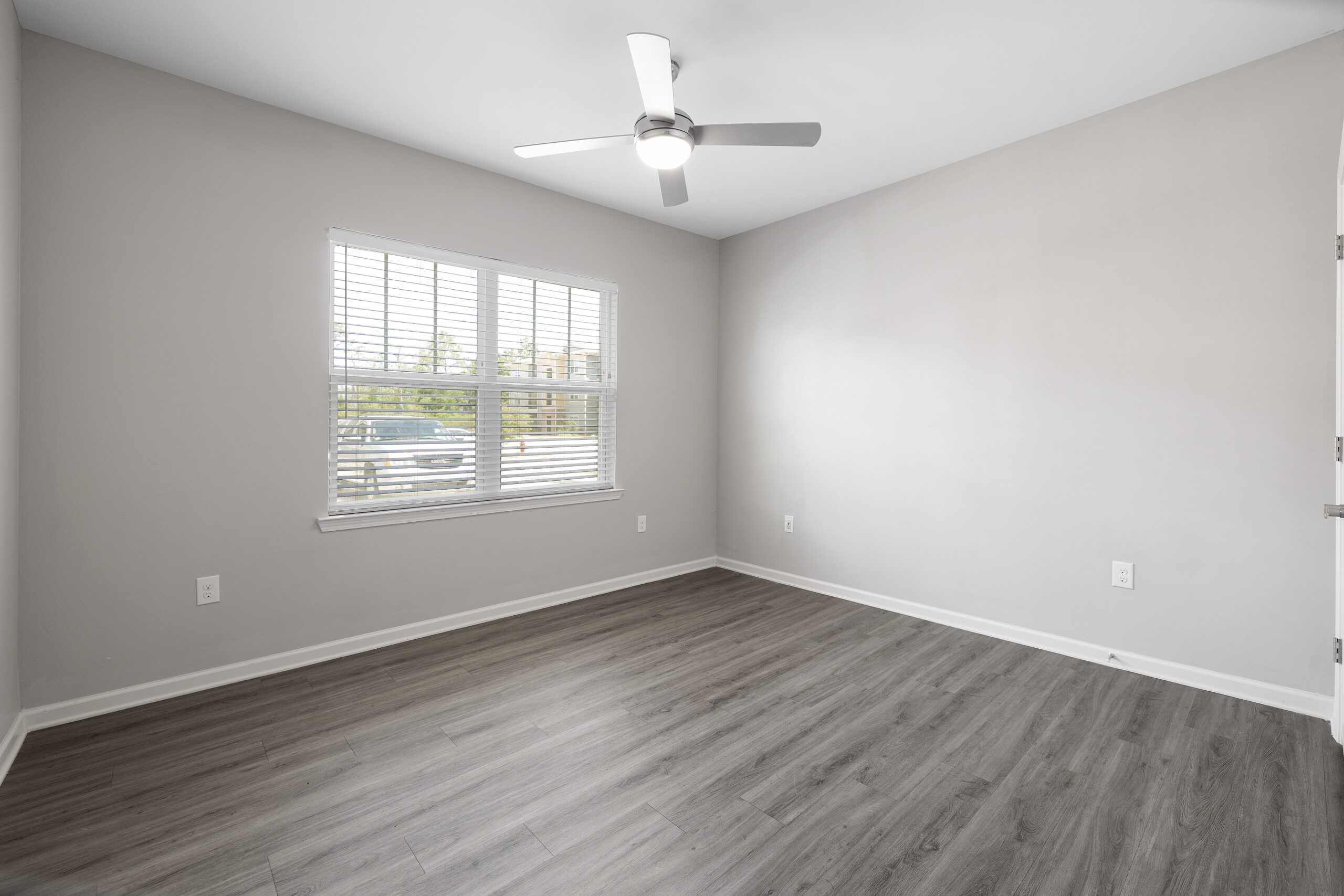 A beige room featuring hardwood-style flooring and a window at Le Jolliet in Lake Charles, LA.