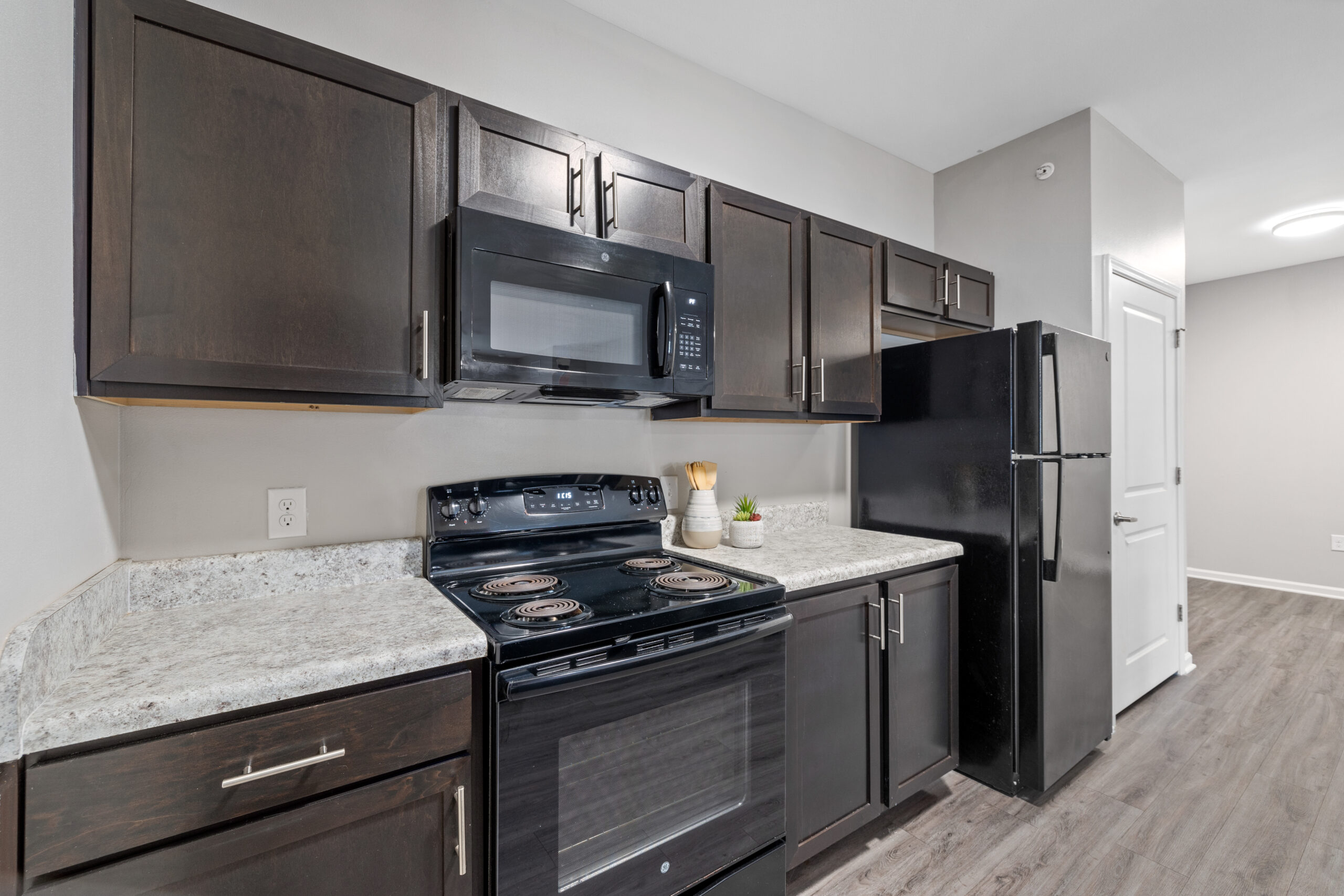 Kitchen at Le Jolliet Apartments featuring black and stainless steel appliances and hardwood-style flooring.